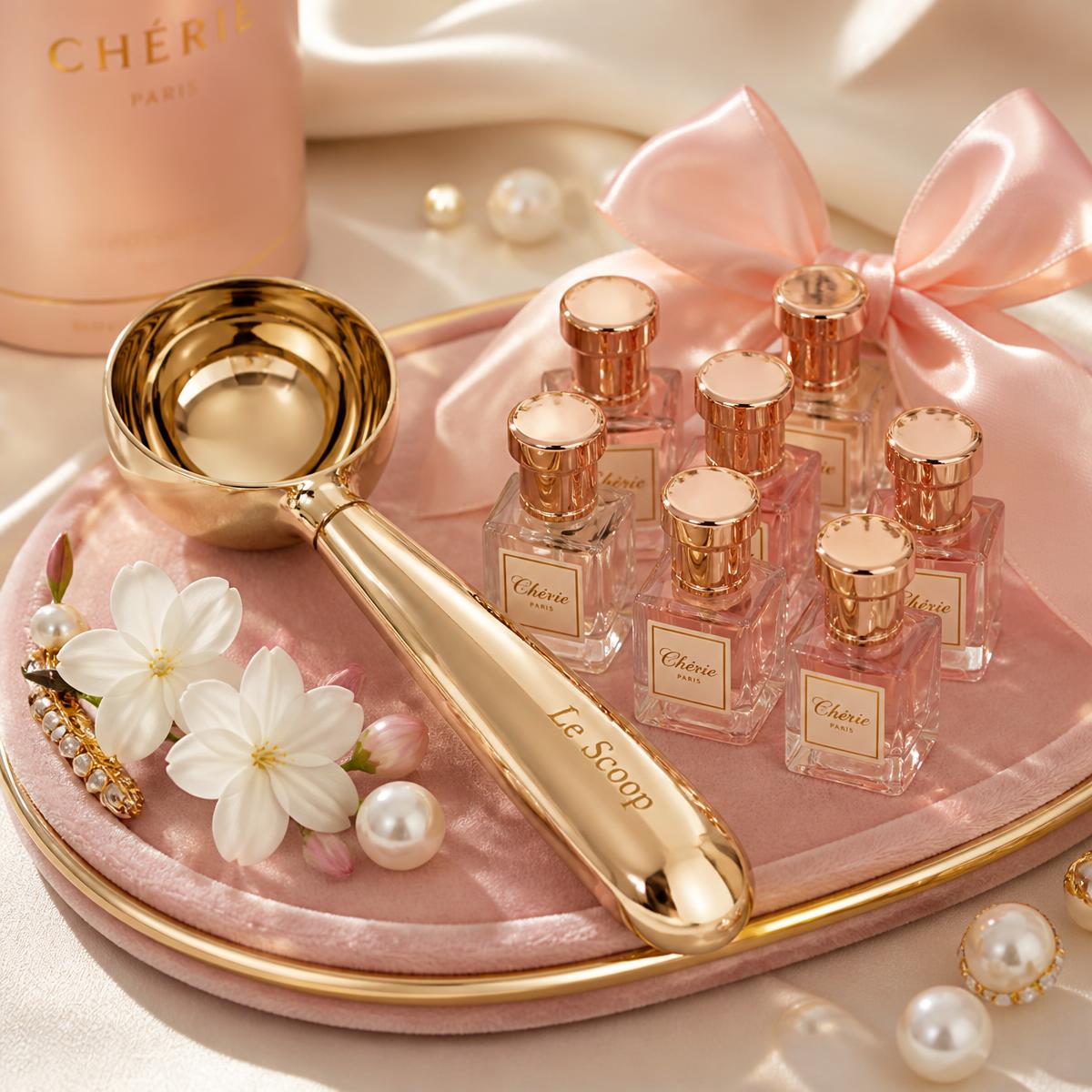 Gold scoop resting on a blush velvet tray beside miniature perfume bottles